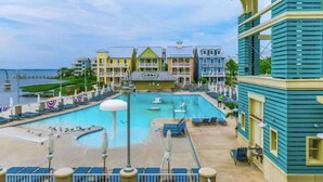 A hotel with a pool, beach view, and colorful buildings. - Coastal retreat with beach and shared pool - balconies, AC, & W/D (Ocean City)