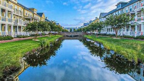A canal with buildings on either side, a stone bridge in the middle, and a clear sky. - Coastal retreat with beach and shared pool - balconies, AC, & W/D (Ocean City)