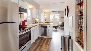 Una cocina moderna con electrodomésticos de acero inoxidable, lavavajillas y piso de madera.