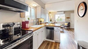 Una cocina moderna con electrodomésticos de acero inoxidable, armarios blancos y encimera de madera.