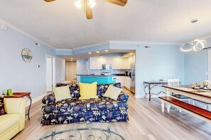 A living room with a sofa, a dining table, and a kitchen in the background. - 4100 #205 (Ocean City)
