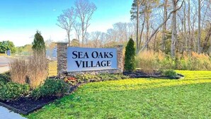 Skilt for Sea Oaks Village, med stensokkel og græsplæne foran.