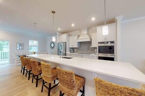 Una cocina moderna con una isla central, taburetes de bar y electrodomésticos de acero inoxidable.