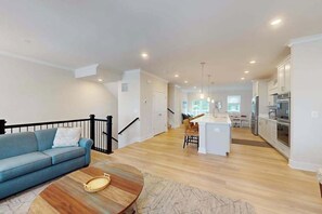 Una sala moderna con un sofá, una mesita de centro y una cocina al fondo.