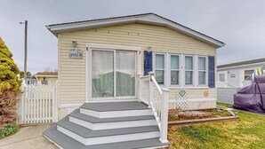 Une maison mobile de plain-pied, dotée d’un porche à l’avant, d’une boîte aux lettres et d’un petit jardin.