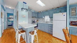 Une cuisine avec des meubles bleus, un réfrigérateur blanc et un plancher en bois.