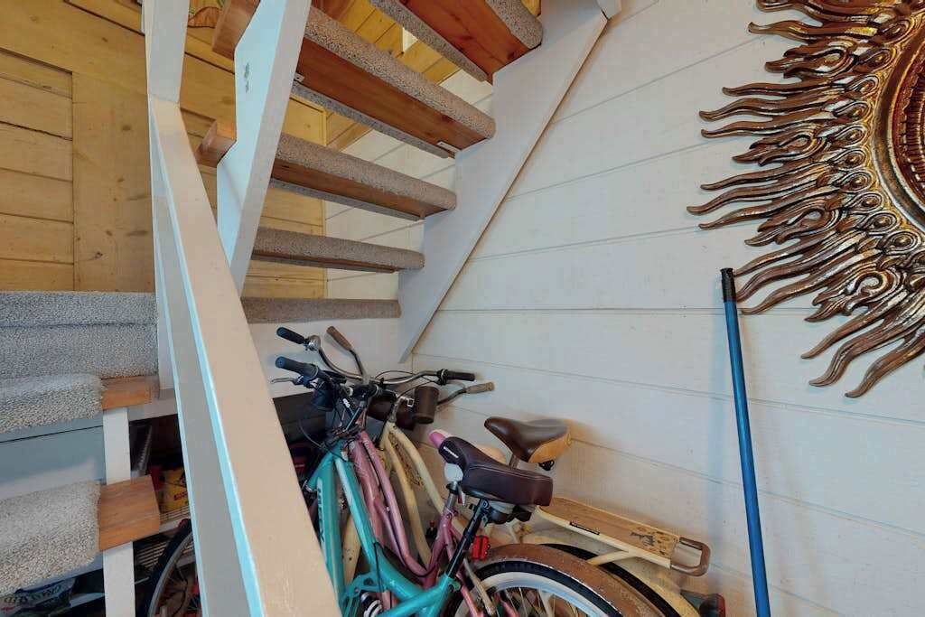 Een trap met houten balken, een fiets en een muur met een zonachtige afbeelding.