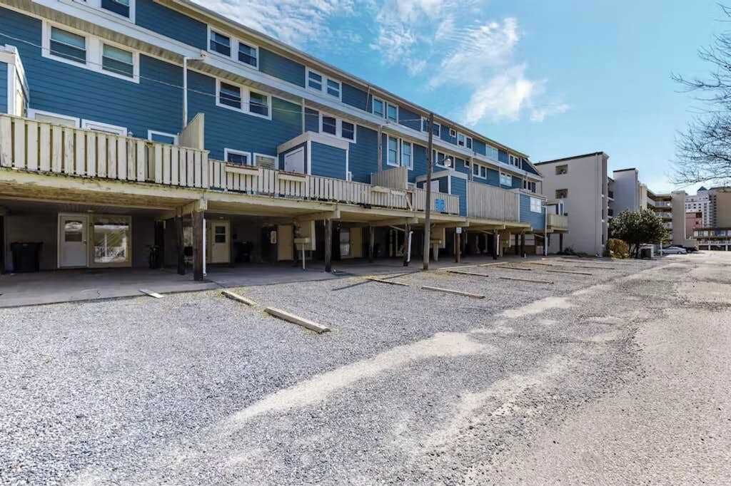 A multi-story building with a parking lot in front.