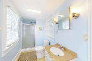 Een badkamer met douche, toilet en wastafel.