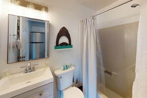 Ein Badezimmer mit Waschbecken, Spiegel, Toilette, Dusche und Handtuchhalter.