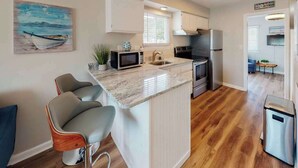 A compact kitchen with a central island, a microwave, a sink, and a stove. - Al-Be Vacation Villas, Unit 1 (Ocean City)
