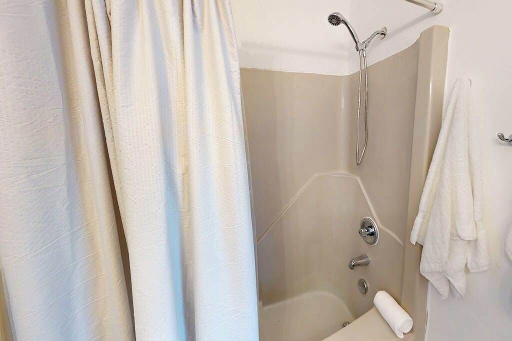 A bathroom with a shower, a bathtub, and a towel rack.