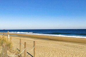 Ein sandiger Strand mit einer Holzumzäunung und blauem Himmel.