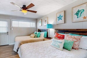 A bedroom with two beds, a ceiling fan, framed artwork, and a door. - Renovated bayfront condo with water-view balcony & fast WiFi - walk to beach (Ocean City)