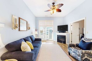 A living room with a sofa, a patterned armchair, a fireplace, and a television. - Harbour Club 5E (Ocean City)