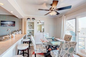 A modern kitchen with a bar area, dining table, and chairs. - Fantastic waterfront escape with furnished deck, WiFi, shared pool & central AC (Ocean City)