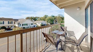 Un balcon avec une balustrade en bois, une table et deux chaises.