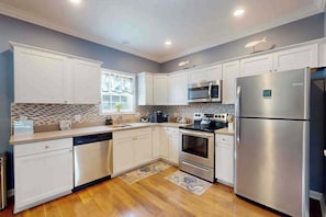 A modern kitchen with white cabinetry, stainless steel appliances, and a patterned backsplash. - 28 White Horse Dr (Ocean Pines)