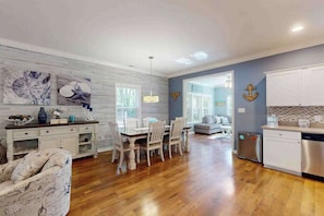 A spacious kitchen with wooden flooring, a dining area with white chairs, and a living room with a sofa. - 28 White Horse Dr (Ocean Pines)