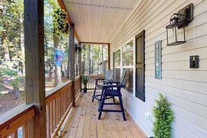 Une terrasse en bois avec un porche abrité, une pancarte de bienvenue et une lanterne fixée au mur.