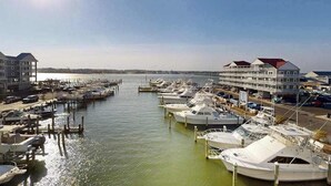 A marina with boats docked, a clear sky, and buildings with red roofs. - Luxury - bay view condo with balcony, pool, W/D, AC & a short walk to the beach (Ocean City)