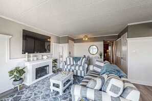 Ein Wohnzimmer mit Kamin, gestreifter Couch und einem an der Wand befestigten Fernseher.
