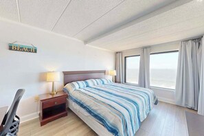 Ein Hotelzimmer mit einem Bett, zwei Nachttischlampen, einem Nachttisch, einem Sessel und einem Schild an der Wand.