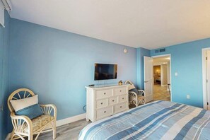 Ein Schlafzimmer mit einem Bett, einem Schminktisch, einem Fernseher und einem Sessel.