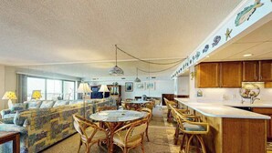 Ein geräumiger Wohnbereich mit einer Couch, einem Esstisch und Stühlen, einer Küche mit Holzschränken und einer Zierdecke.