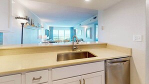 A kitchen with a sink, dishwasher, and white cabinets. - Triton's Trumpet B502 (Ocean City)