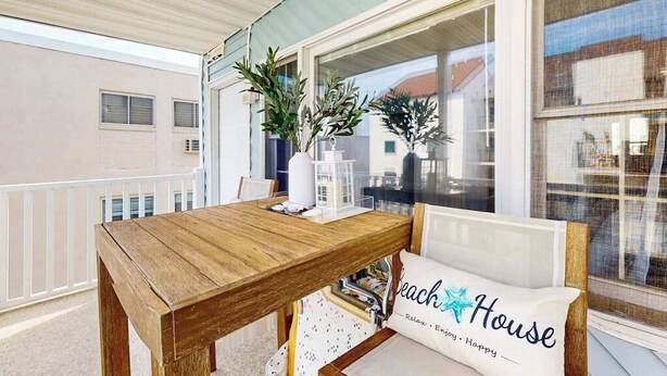 A wooden table with a white vase and two potted plants on a balcony with a white railing. - Bonnie Belle 208 (Ocean City)