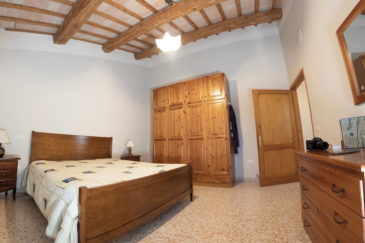 Ein Schlafzimmer mit einem hölzernen Bett, einem Kleiderschrank, einer Kommode und einem Spiegel.