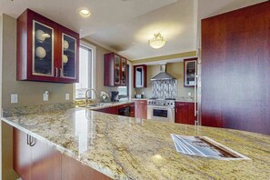 A kitchen with granite countertops, stainless steel appliances, and wooden cabinets. - Luxurious Ocean Front Condo w/Beach Access, Central AC & Gas Fireplace (Ocean City)