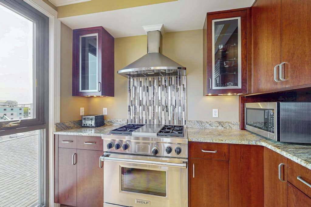 A modern kitchen with a gas stove, oven, microwave, and wooden cabinets.
