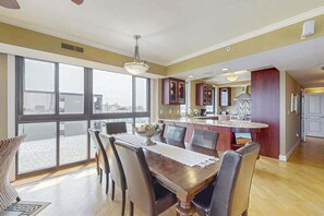 A dining area with a large window, a kitchen island, and a view of the city. - Luxurious Ocean Front Condo w/Beach Access, Central AC & Gas Fireplace (Ocean City)