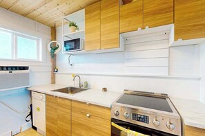 A modern kitchen with wooden cabinets, a built-in microwave, a stainless steel stove, and a sink.
