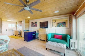 Ein gemütliches Blockhaushaus-Interieur mit Holzbalkendecke, einem grünen Sofa, einem Essbereich und einer Küche.