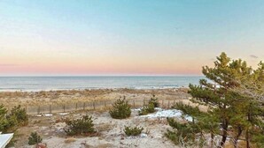 Un paisaje costero con playa, vegetación escasa y cielo despejado.