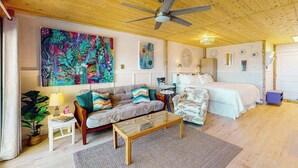 Una habitación acogedora con cama, sofá, mesa de centro y ventilador de techo.