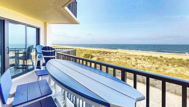 A balcony with a view of the beach, a table, and chairs. - Stunning Ocean front condo w/beach & ocean views, AC & shared pool (Ocean City)
