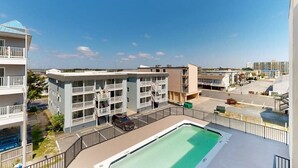 A multi-story hotel with balconies, a swimming pool, and a parking area. - Stunning Ocean front condo w/beach & ocean views, AC & shared pool (Ocean City)