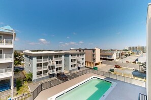 Ein mehrstöckiges Hotel mit Balkonen, einem Schwimmbad und einem Parkplatz.