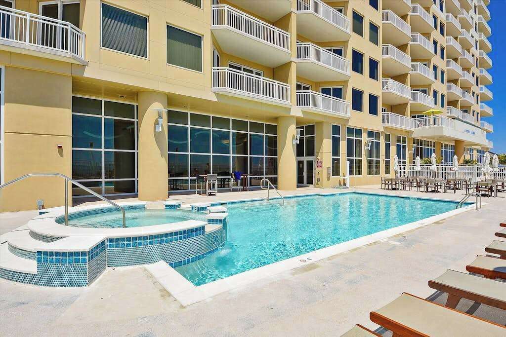 Un hotel con piscina, varios balcones y mobiliario exterior.