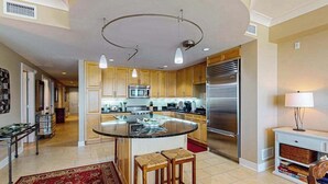 Een moderne keuken met een centraal eiland, roestvrijstalen apparatuur en houten kasten.