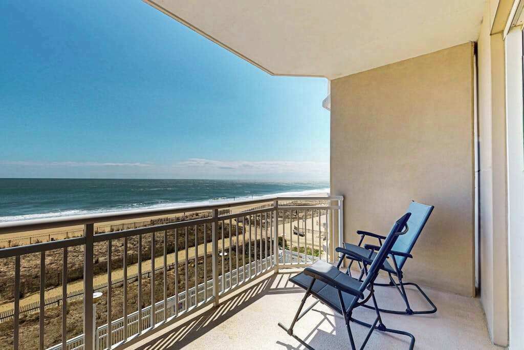 Un balcón con vista al océano, una silla y una barandilla.