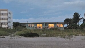 En byggnad som ligger vid stranden, med flera fönster, en balkong och utsikt över havet.