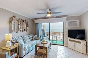 Una sala de estar con sofá, mesa de centro, televisor y balcón con vistas.