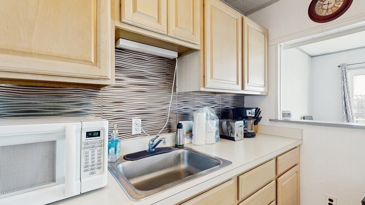 A kitchen with a microwave, sink, and cabinets.