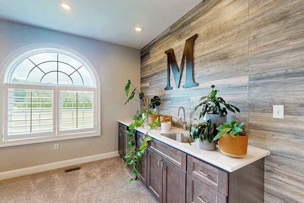 A kitchen with a large wooden wall, a window with a view, and a sink with plants. - 3 Ladies Estate (Bishopville)