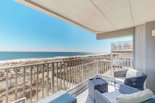 A balcony with wicker furniture, a view of the beach, and a railing. - Oceanfront Condo with Balcony, Beach Access, Central AC, WiFi & Washer/Dryer (Ocean City)